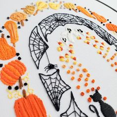 an embroidery pattern with pumpkins, spider web and cat