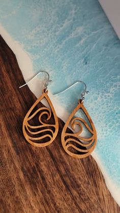 wooden earrings with spiral design on the front and back of them, sitting on top of a wood table