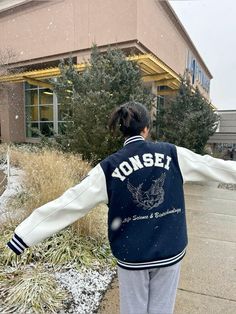 a woman in a blue and white jacket is walking down the street with her arms outstretched