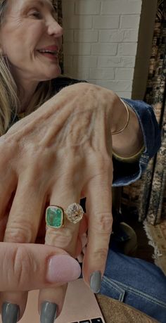 a woman is showing off her engagement ring with an emerald on it's finger