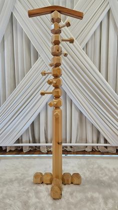 a tall wooden pole with multiple crosses on it's sides in front of white drapes