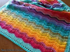 a multicolored crocheted blanket sitting on top of a wooden table