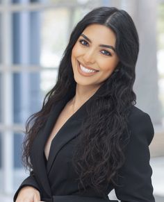 a woman with long black hair is smiling and holding a piece of paper in her hand