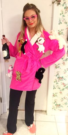 a woman in a pink bathrobe holding a wine bottle and stuffed animal toy