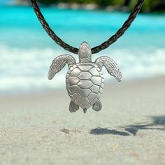 a turtle necklace is shown on the beach