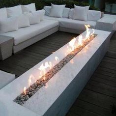 an outdoor fire pit with white couches and pillows