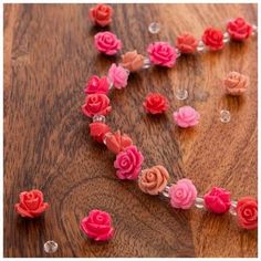 pink and red flowers are arranged in the shape of a heart on a wooden table