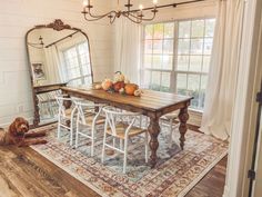 a dining room table with chairs and a large mirror on the wall next to it