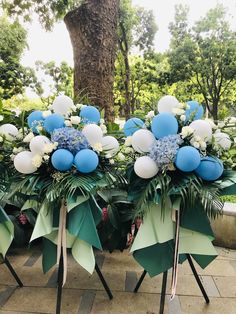 blue and white bouquets are on display in front of a tree at a park