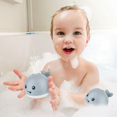 a baby in the bathtub with soap on his face and two whale shaped bubbles coming out of it's mouth