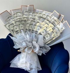 a bunch of money sitting on top of a blue chair with white ruffles