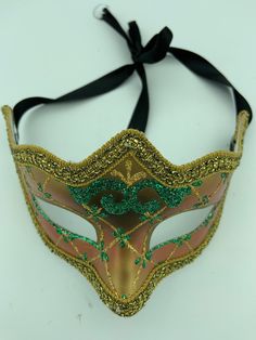 "This is a very nice original handmade and hand painted Venezia masquerade face mask made in Italy. The design on the shiny gold and orange face mask features turquoise blue and multi-color glitter with a border of gold lace and gold rope around the edges. It comes with a black ribbon tie and is stamped on the back \"Original Hand Painted Made in Italy Venezia\". The mask measures approximately 6 5/8\" long and 3 3/4\" wide and is in very good preowned condition with light wear on the back of th Green Carnival Masks And Prosthetics, Green Masks For Carnival Costume Party, Green Masquerade Mask For Mardi Gras, Green Mask For Masquerade Carnival, Green Masks For Masquerade Carnival, Green Masquerade Mask For Mardi Gras Party, Green Masks For Carnival Masquerade, Green Masks And Prosthetics For Carnival Costume Party, Green Eye Mask For Masquerade