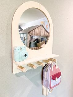 a mirror hanging on the side of a wall next to a purse and camera bag