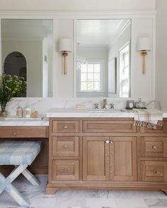 a large bathroom with two sinks, mirrors and a bench in the middle of it