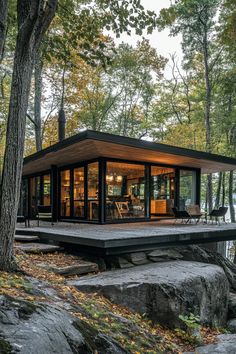 a modern cabin in the woods surrounded by rocks and trees with an open floor plan