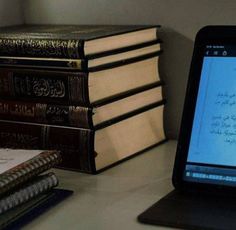 an open laptop computer sitting on top of a desk next to books and notebooks