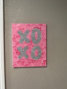 a pink and silver wall hanging with the word xo on it's side