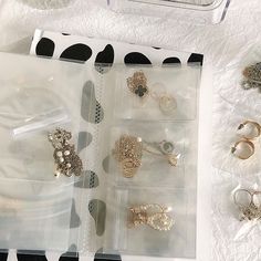 several pairs of jewelry are in a clear case on a white sheet with black and white polka dots