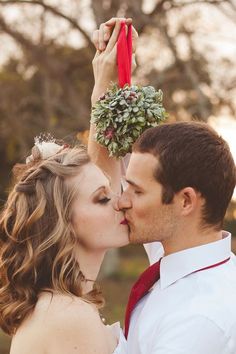 a man and woman kissing each other in front of trees