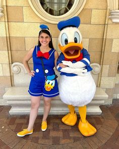 a woman standing next to a donald duck mascot