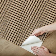 a woman is holding a piece of paper on top of a rug that has holes in it