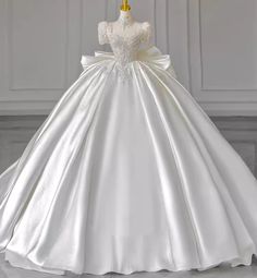 a white wedding dress on a mannequin stand in front of a wall and floor