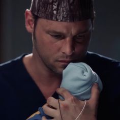 a man holding a baby in his arms and wearing a hat on top of his head