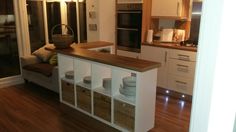 a kitchen with white cabinets and wooden counter tops next to a door leading into the living room