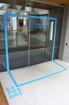 the entrance to an office building with glass doors and blue tape on the floor that says exosure