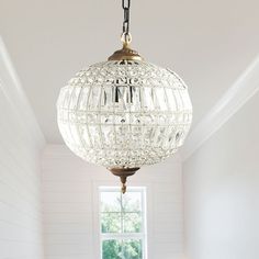 a chandelier hanging from the ceiling in a room with white walls and wood flooring