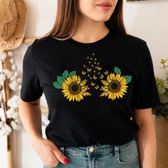 a woman wearing a black t - shirt with sunflowers on it