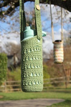 a green crocheted bag hanging from a tree with two jars in the background