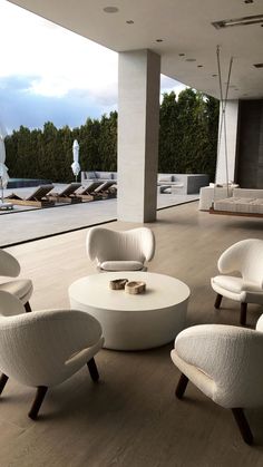 a living room filled with white furniture next to a large open floor plan on top of a hard wood floor