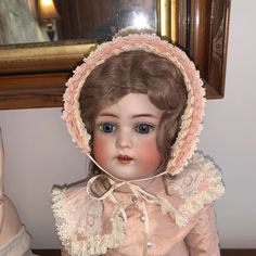 an antique doll is sitting on a table in front of a mirror with a hat on it's head