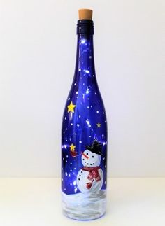 a glass bottle with a snowman painted on the side and stars in the sky