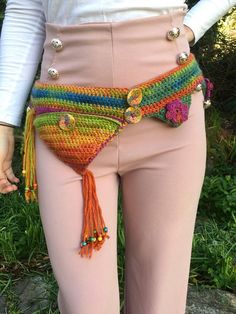 a woman in pink pants with a multicolored crochet purse on her hip