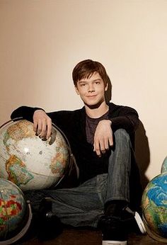 a young man sitting on the floor with several globes