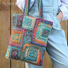 a crocheted bag is being held by a woman in overalls and white shirt