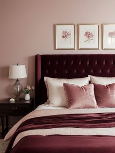 a bedroom with pink walls and purple bedding, two framed pictures on the wall