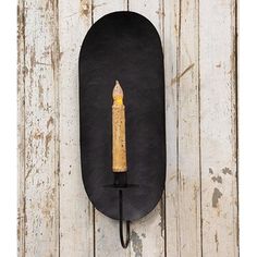 a candle on a wall with a hook in the shape of an oval and black board