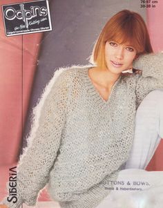 the woman is wearing a sweater and posing