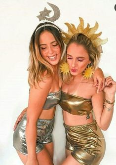 two beautiful young women standing next to each other wearing gold clothing and headbands