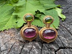 "These bold earrings are set in 18k yellow gold and drenched in sophistication.  They date from the 1980's.  The oval shaped  mounting  has  beautifully scrolled rims of gold that come to a point, acting as the  backdrop that hold,  in the center,  a deep rich oval pink tourmaline.  Right above the pink tourmaline is an oval  shaped forest green tourmaline. All set east to west creating the chicness.    The pink tourmaline measures approx. 11 mm x 14 mm.   The green tourmaline measures 6.5 mm x Luxury Classic Tourmaline Jewelry, Luxury Tourmaline Dangle Jewelry, Tourmaline Earrings, Bold Earrings, Earrings Pink, Green Tourmaline, Pink Tourmaline, The Pink, Forest Green