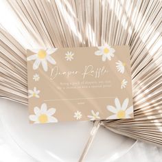 a paper fan with daisies on it sitting on top of a plate next to a napkin