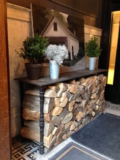 there are some potted plants on top of a firewood log fireplace mantel