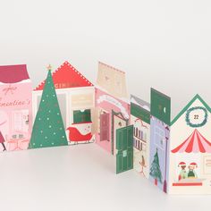 several small paper houses with christmas decorations on them, all in different colors and shapes