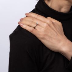 a woman's hand with a ring on her left wrist, wearing a black turtle neck sweater