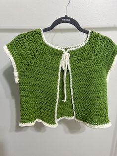 a green crocheted sweater hanging on a wall