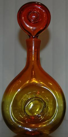 an orange glass vase sitting on top of a table