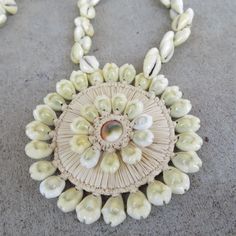 This lovely necklace has a huge pendant that measure 3 3/4" wide. It is made with a mix of cowrie shells, wicker and a ceramic bead in the center sometimes called an eye. The strand measures 30" in length but the overall measurement is 36" Very cool hippie vibe or Island theme. Jewelry shelf A drawer 1 061023 Artisan Beaded Necklace In Natural Color For Beach, Bohemian Beaded Pendant Necklace For Beach, Beaded Necklaces For Vacation, Natural Beaded Necklaces For Vacation, White Bohemian Necklace With Large Pendant, Bohemian White Necklace With Large Pendant, Beige Bohemian Shell Jewelry, Bohemian Beige Jewelry For Vacation, Handmade Shell Pendant Necklace For Vacation